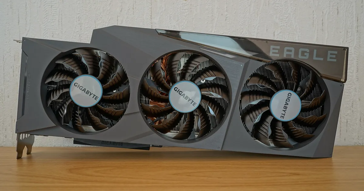 A Gigabyte GeForce RTX 3090 graphics card with three fans standing on a wooden desk