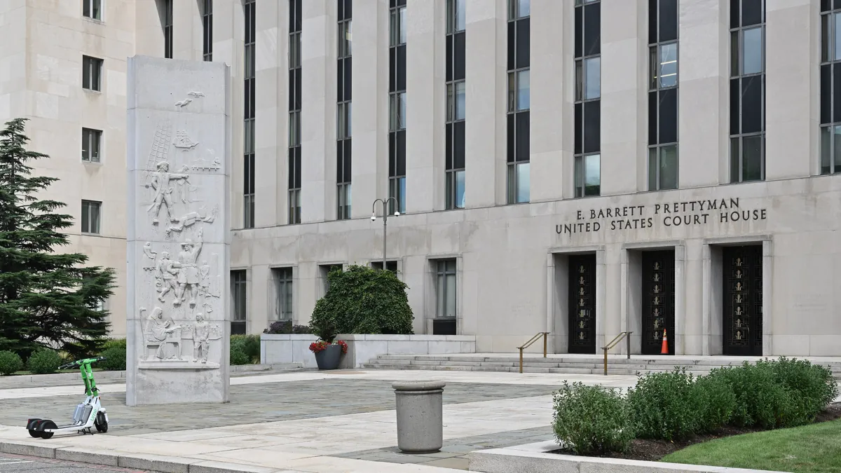 Entrance of the E. Barrett Prettyman United States Court House in Washington, D.C., with a carved stone relief pillar on the plaza