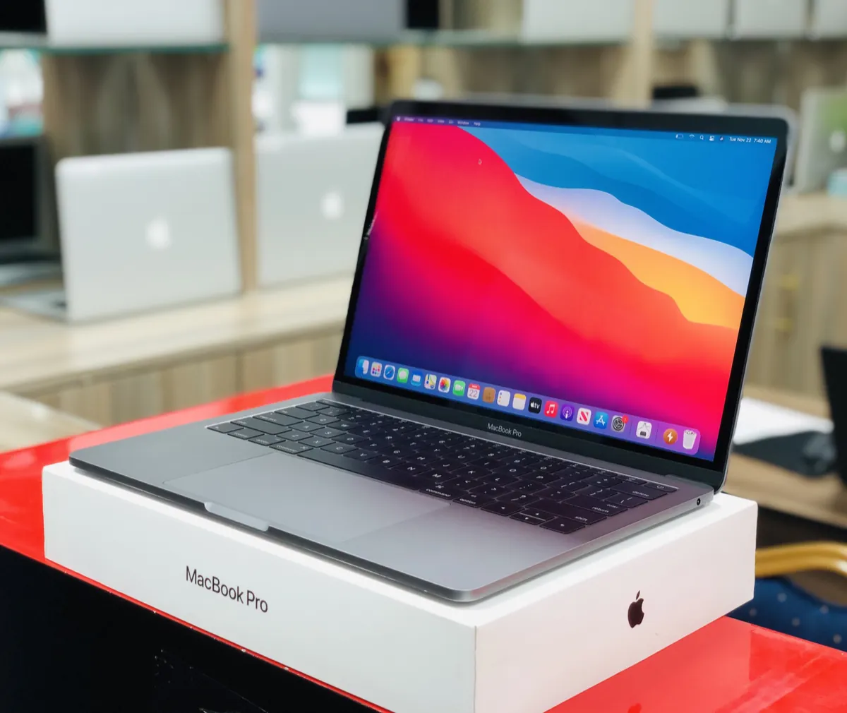 A 2019 13-inch MacBook Pro, an Intel model, open on top of its white retail box in a shop