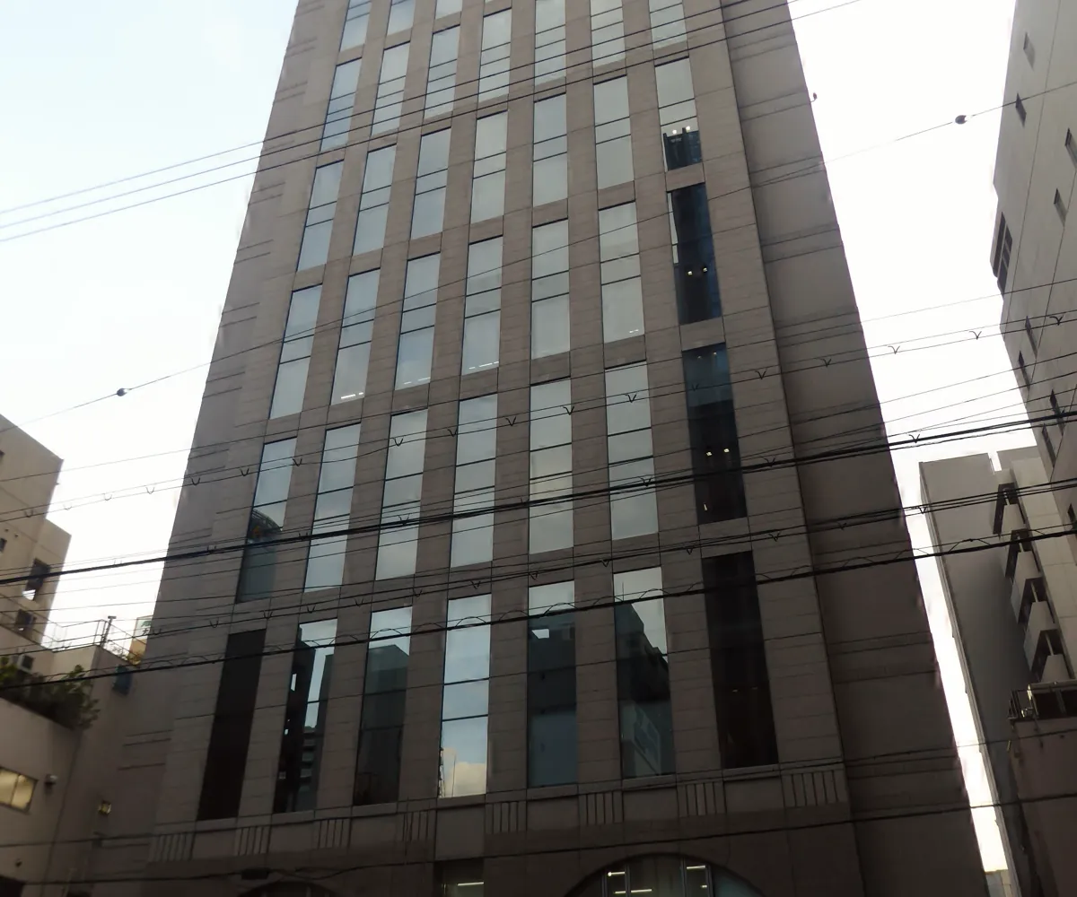 La fachada de piedra y vidrio del edificio de Investigación y Desarrollo de Capcom, una torre de oficinas alta en una calle de la ciudad
