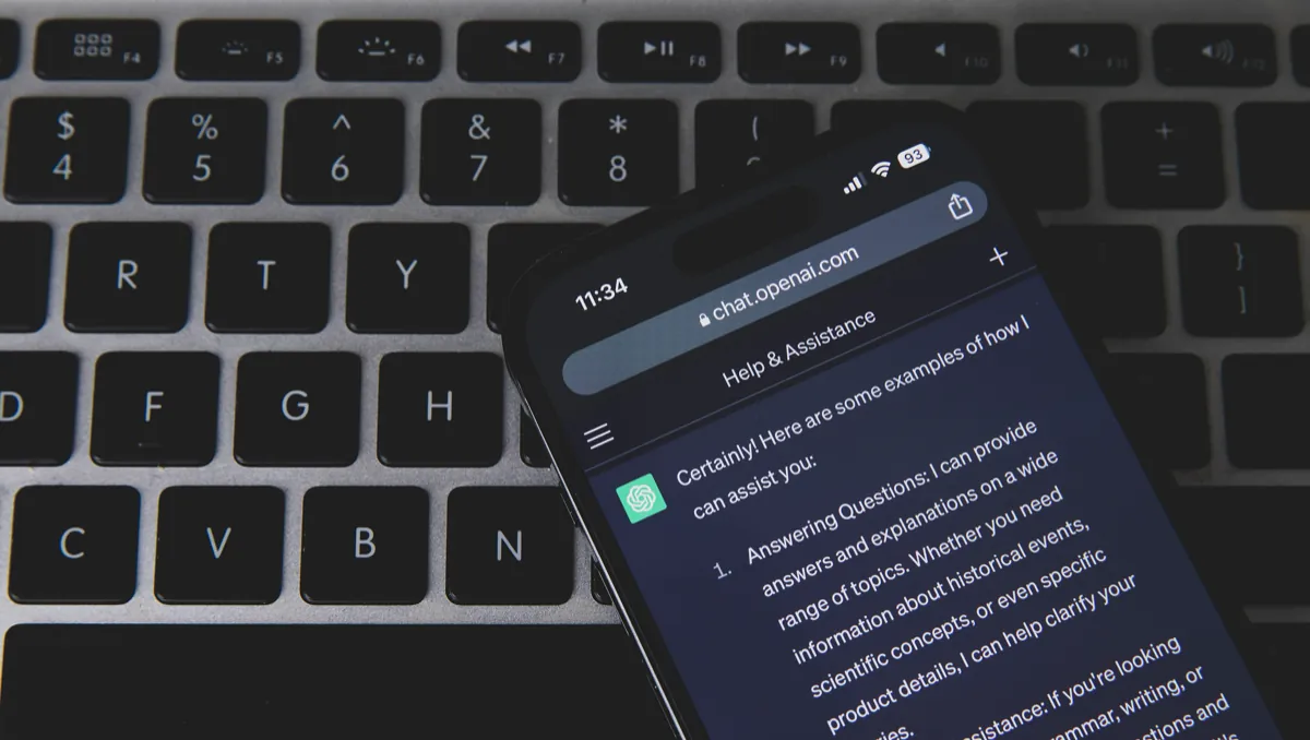 Un celular con una conversación de ChatGPT abierta en el navegador, sobre el teclado de una laptop