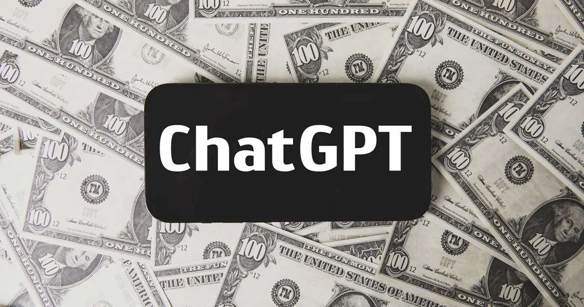 Un celular con la palabra ChatGPT en la pantalla, sobre un montón de billetes de utilería de US$100