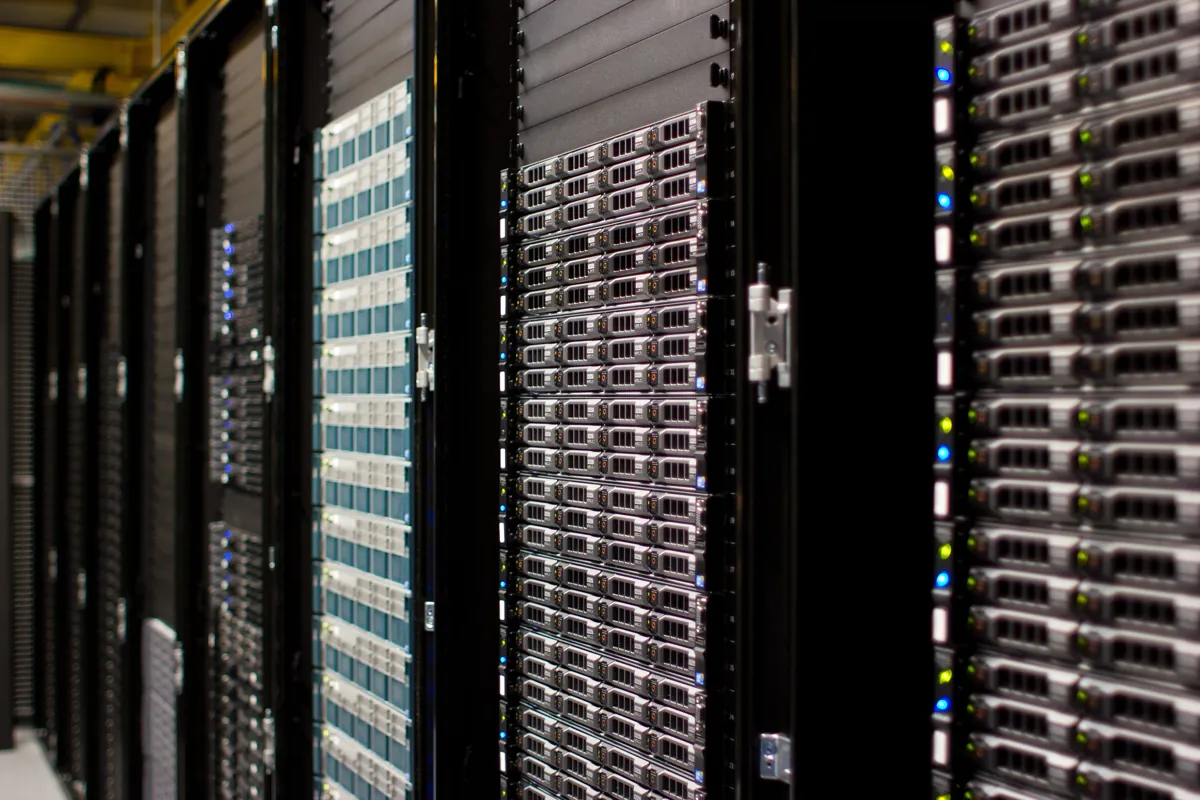Rows of black server racks filled with rack-mounted servers and status lights in a data center aisle
