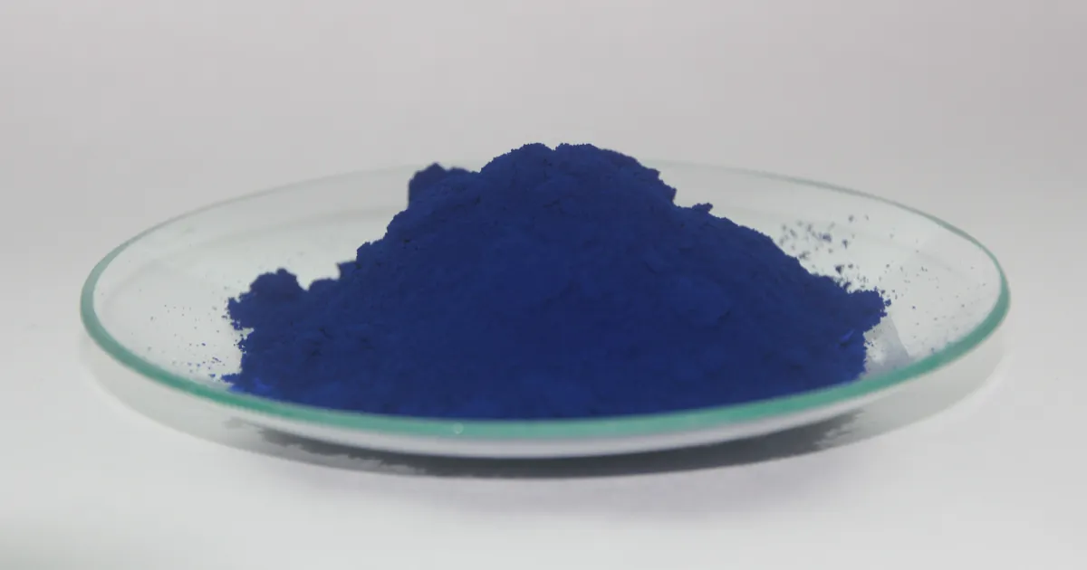 Un montón de pigmento azul de Prusia, en polvo azul intenso, sobre un plato de vidrio poco profundo con fondo blanco