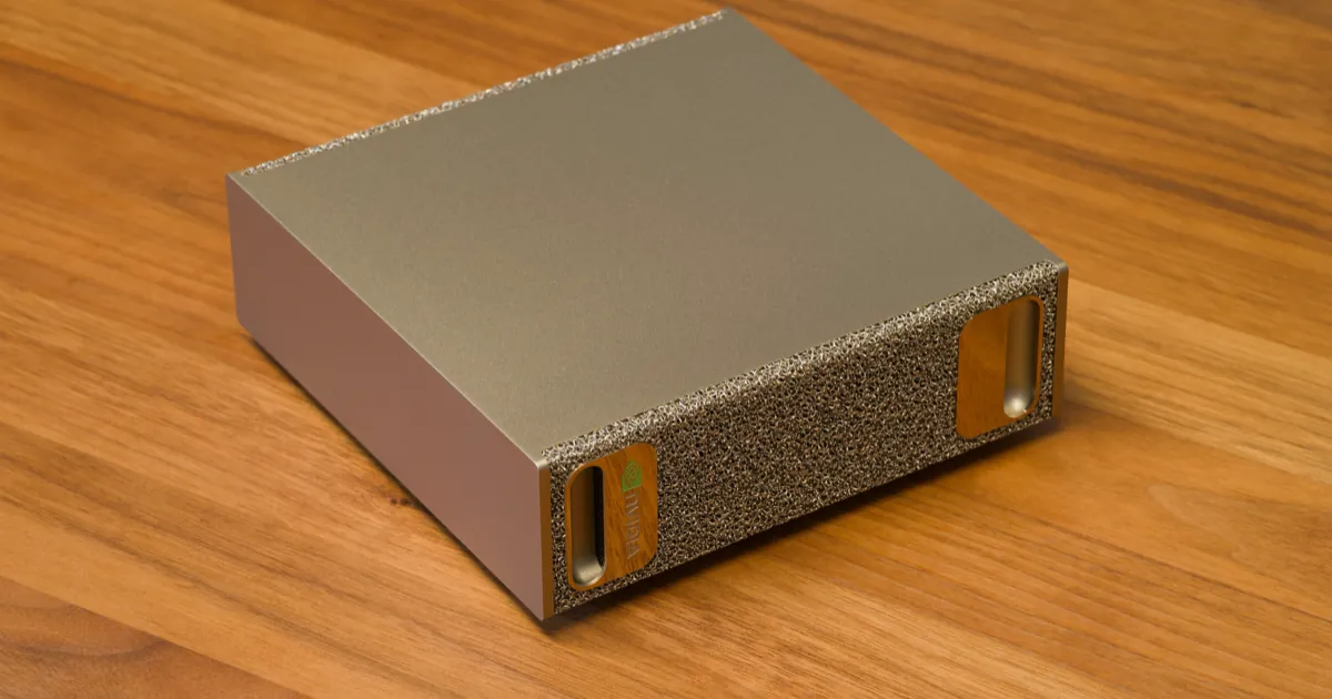 The original 128GB Nvidia DGX Spark, a small gold metal box with foam-textured ends, sitting on a wooden desk