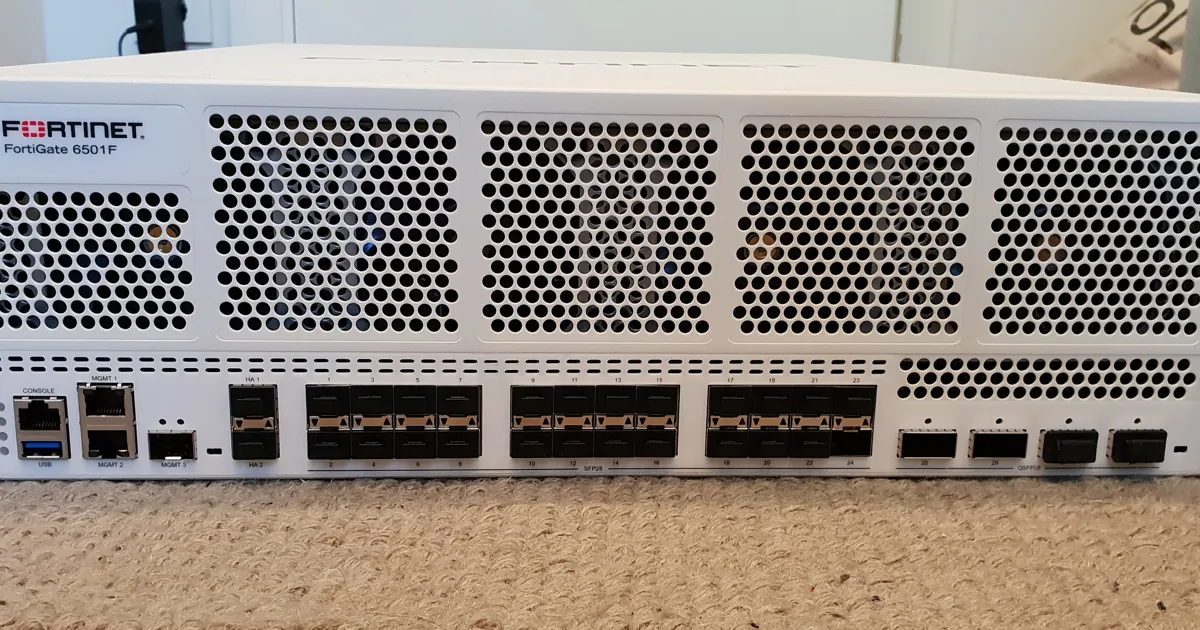Front panel of a white Fortinet FortiGate 6501F firewall with rows of network ports below its ventilation grilles