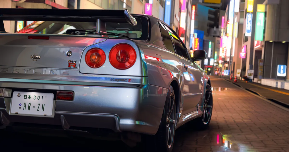 A silver Nissan Skyline GT-R V-Spec II parked on a wet Tokyo street lit by neon signs in Forza Horizon 6