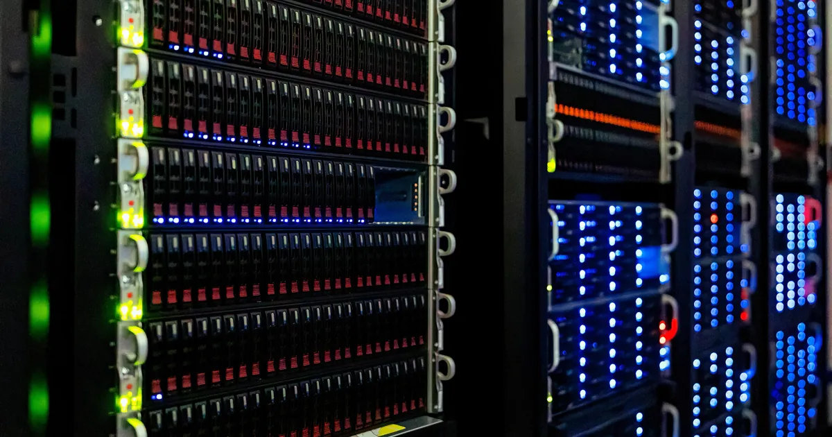 Filas de servidores montados en rack con luces de estado verdes y azules en un cuarto de servidores oscuro