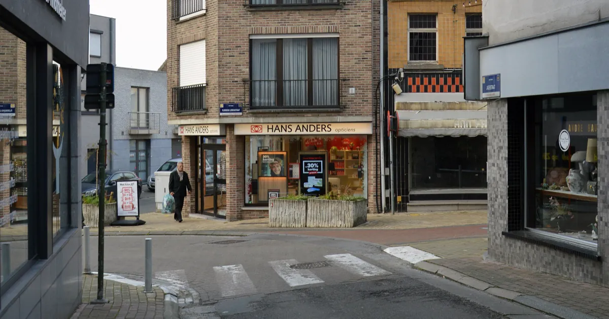 A Hans Anders optician shop on a street corner in Wetteren, Belgium, with a pedestrian walking past the window