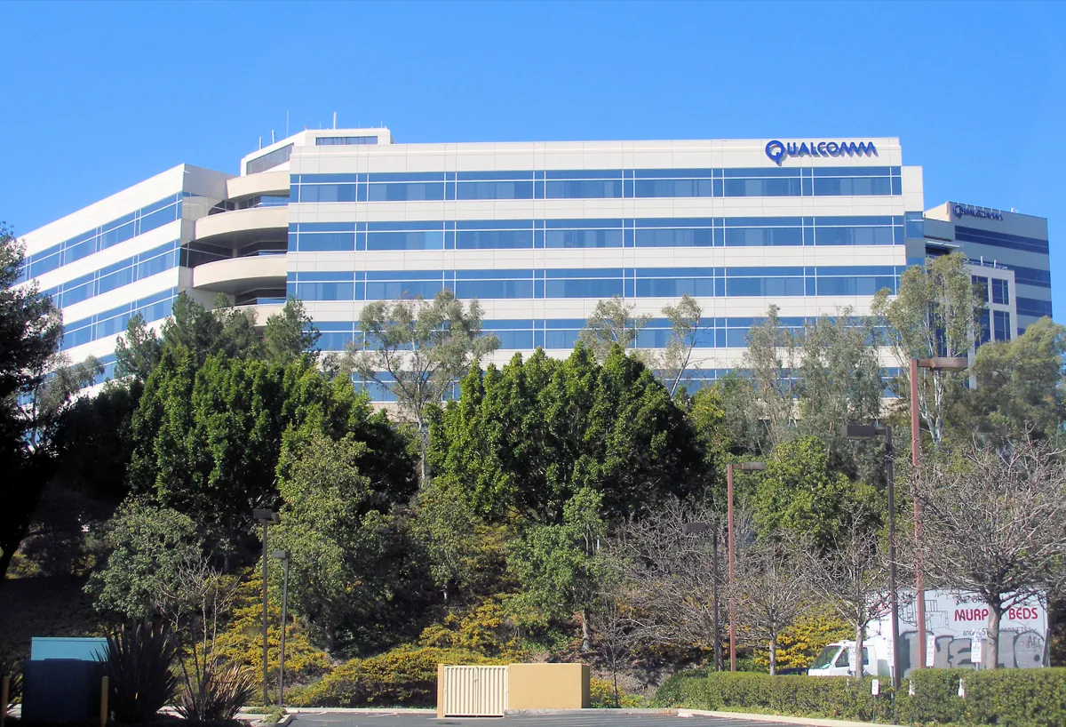 Qualcomm's headquarters building in San Diego, a long white and blue glass office block behind trees