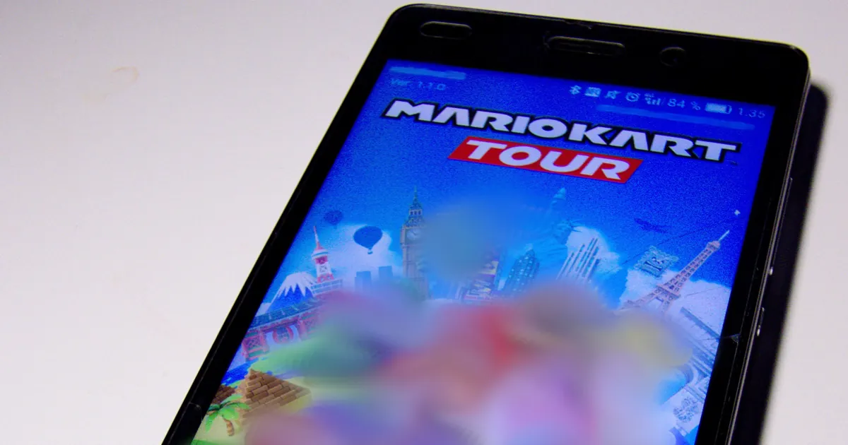 Un celular Android sobre una mesa blanca con la pantalla de título de Mario Kart Tour mientras el juego carga