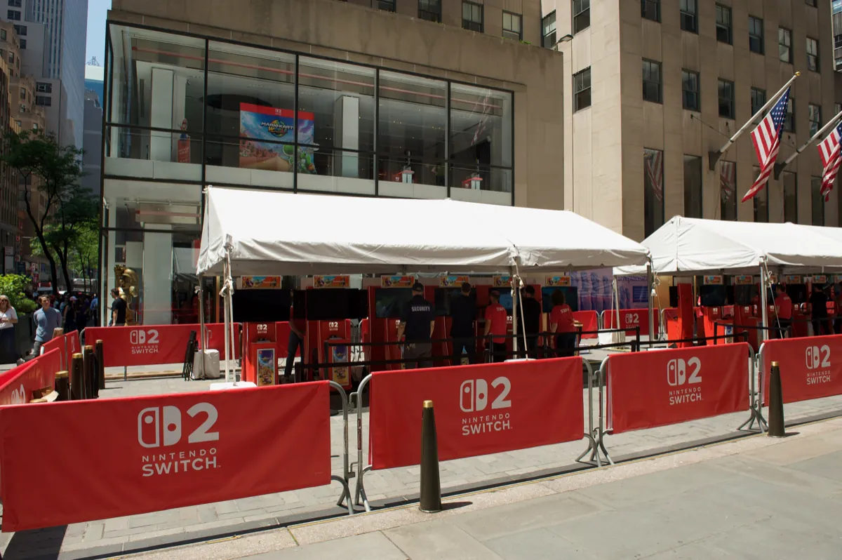 Estaciones de prueba de Nintendo Switch 2 bajo carpas blancas frente a la tienda Nintendo de Nueva York, con un póster de Mario Kart World en la ventana