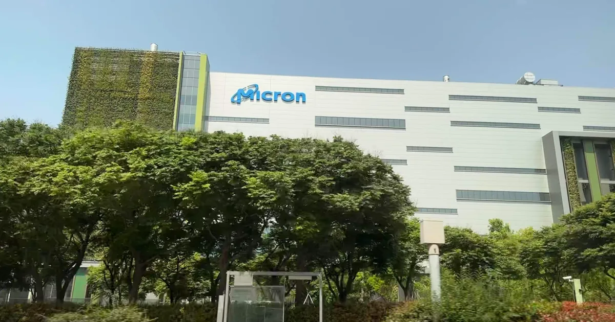 La fábrica de chips de memoria de Micron en Taichung, Taiwán, un edificio blanco con el logo de Micron detrás de árboles