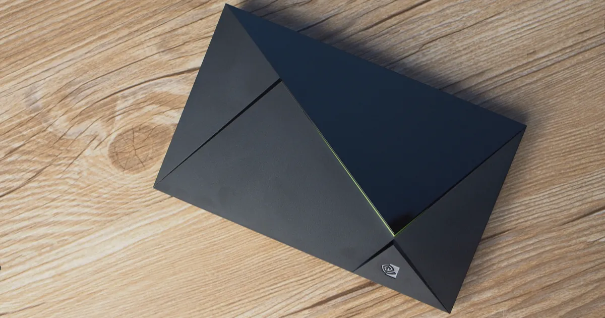 A 2017 Nvidia Shield TV streaming box, a black angular case with a thin green light strip, lying on a wooden table