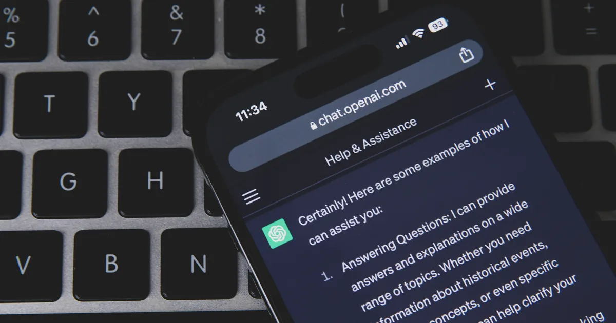 A phone showing a ChatGPT conversation in dark mode, resting on a laptop keyboard