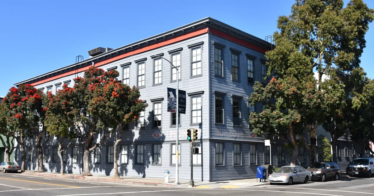 The gray wooden Pioneer Building on a sunny San Francisco street corner, which housed OpenAI's offices in 2019