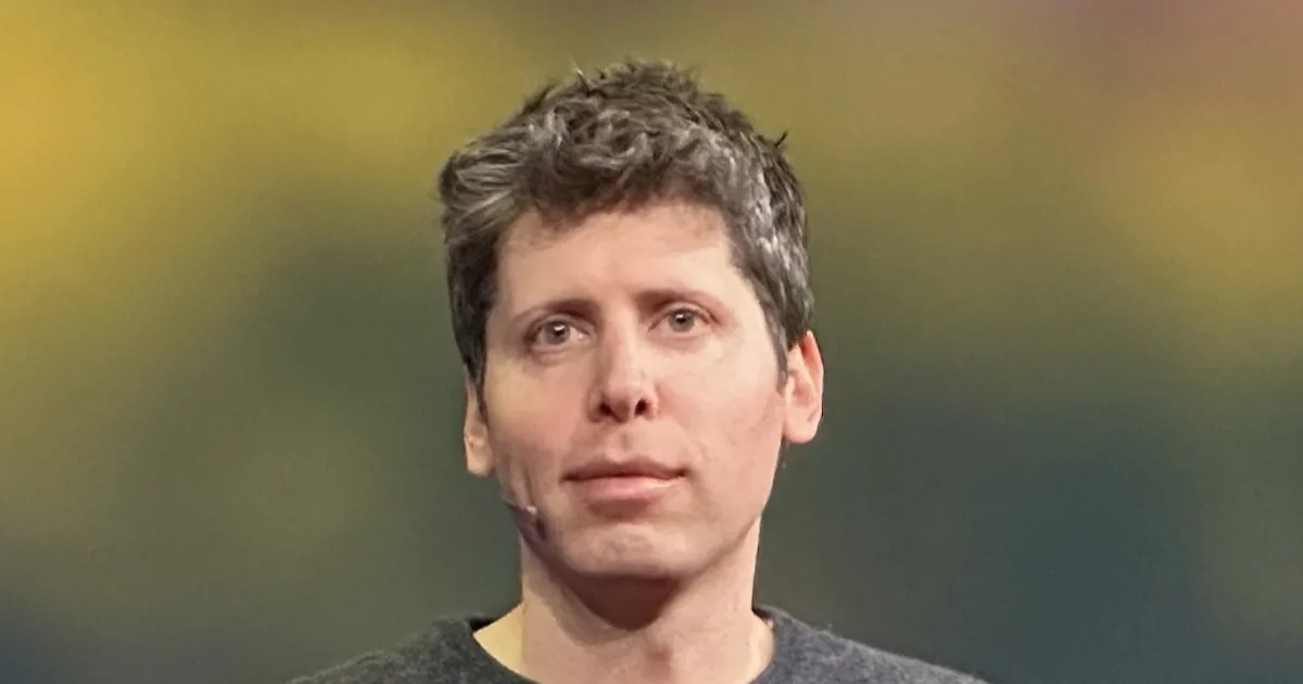 OpenAI CEO Sam Altman on stage at TED in 2025, in a dark gray sweater against a blurred green and yellow background