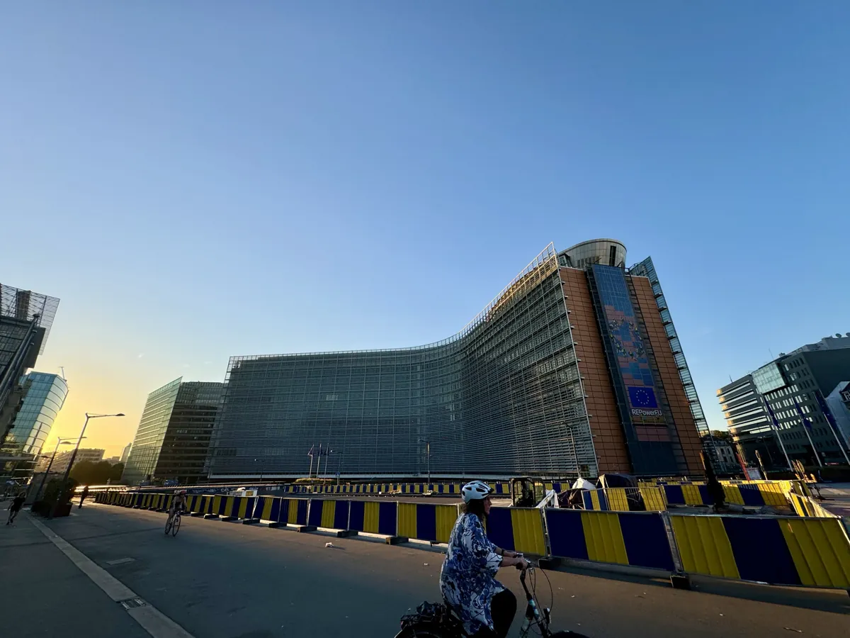 The curved glass Berlaymont building, the European Commission's headquarters in Brussels, at sunset with a cyclist in front