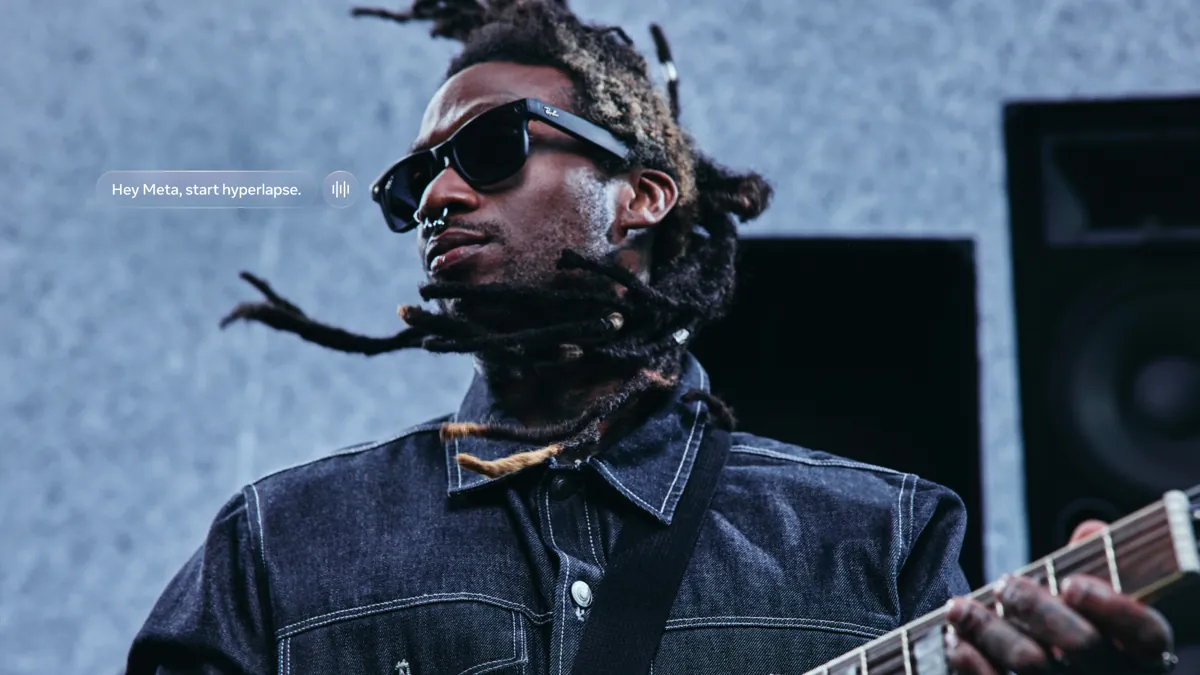 A guitarist wearing black Ray-Ban Meta Gen 2 Wayfarer glasses, with a Hey Meta, start hyperlapse voice prompt beside him