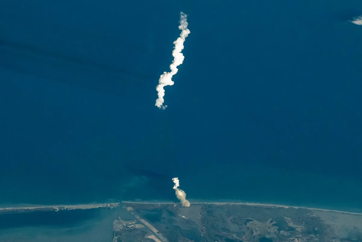 The white exhaust plume of a Starship launch rising over the Gulf coast of Texas, photographed from the International Space Station