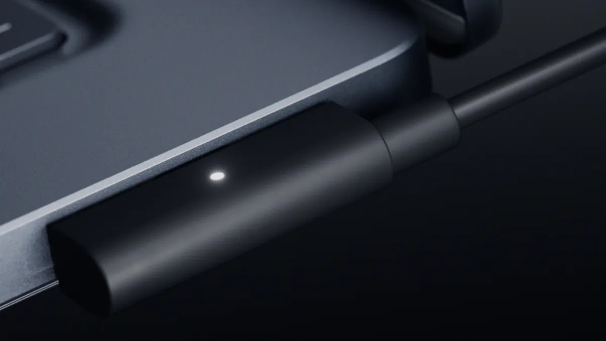 Close-up of the Magnetic Connect charging cable attached to the side of the Surface Laptop Ultra, with a small white status light
